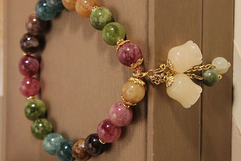 Multicolored beaded bracelet with gold accents on a beige surface