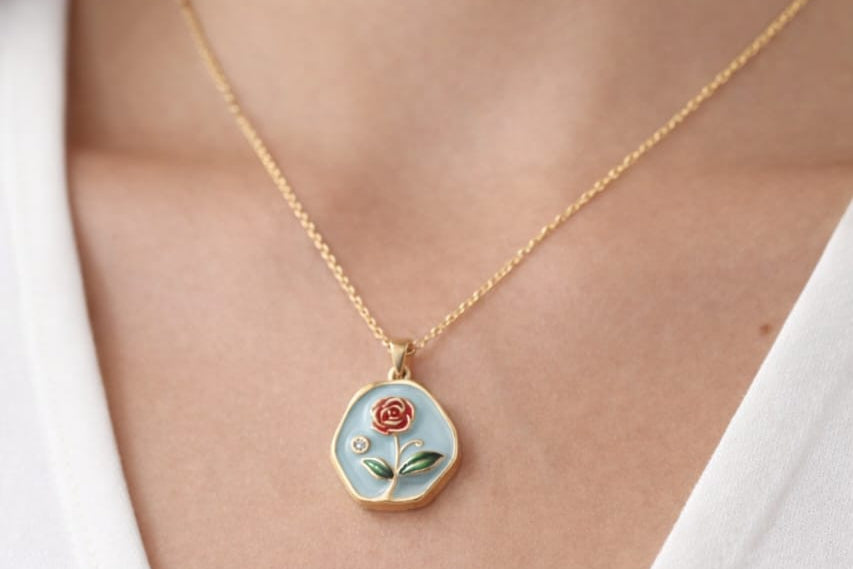 Necklace with a floral pendant worn by a person against a white background