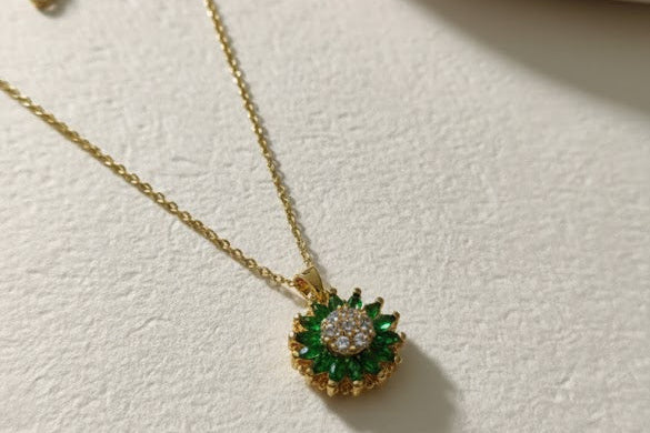 Gold necklace with a green gemstone pendant on a light surface
